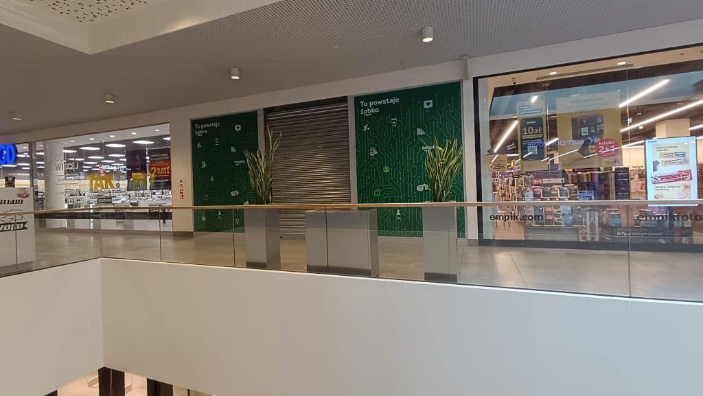 Puste miejsce w centrum handlowym z zamkniętymi drzwiami sklepu Żabka na pierwszym piętrze.