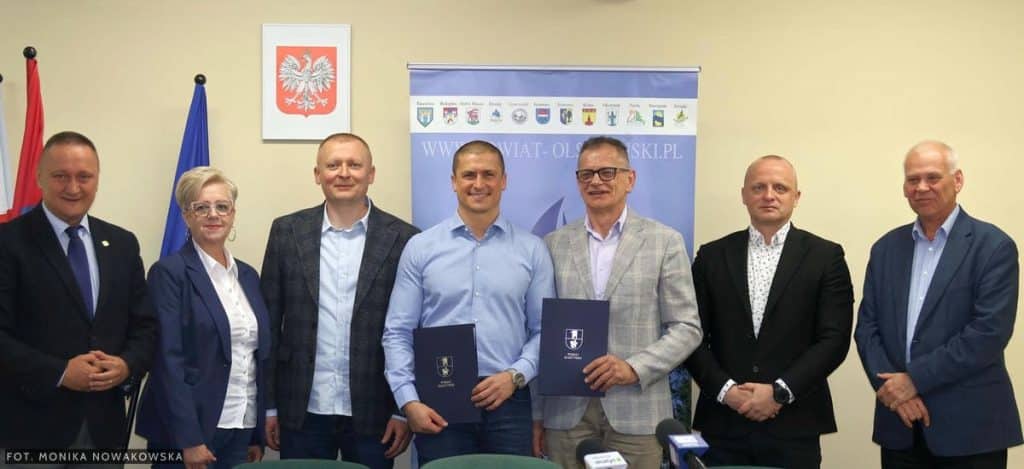 Grupa os&oacute;b na spotkaniu podpisującym umowy na remonty dr&oacute;g w powiecie olsztyńskim.