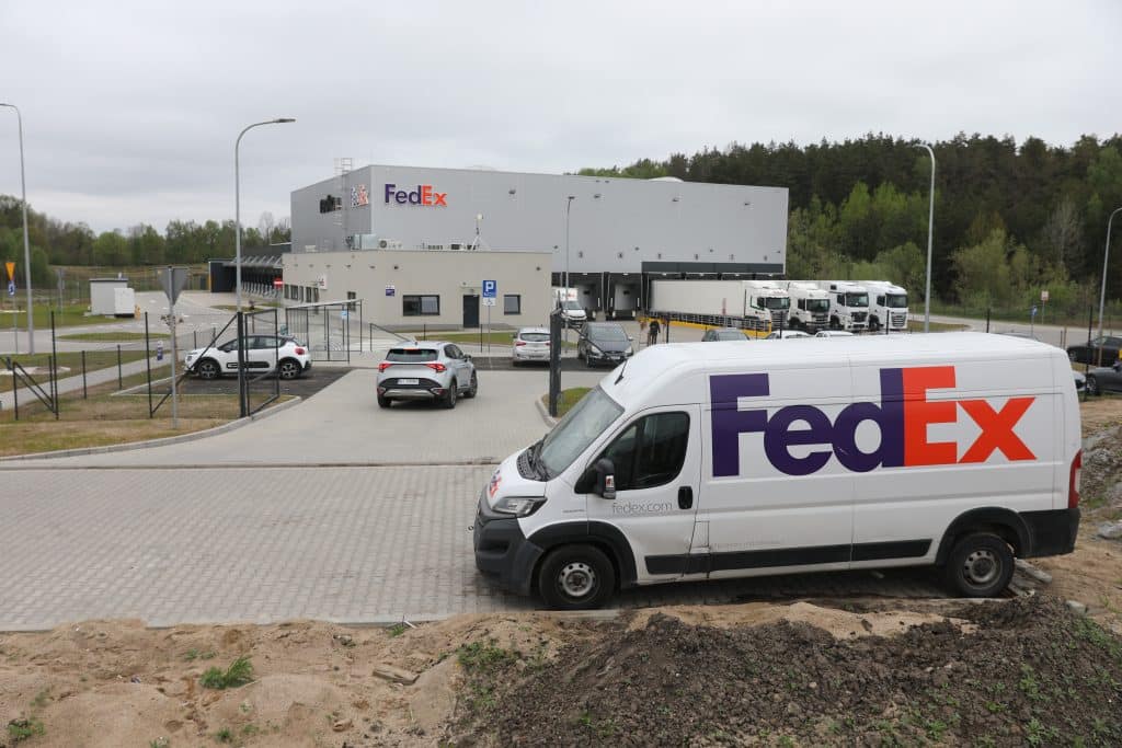 Nowe centrum logistyczne FedEx w Olsztynie, budynek i pojazdy firmy na parkingu.