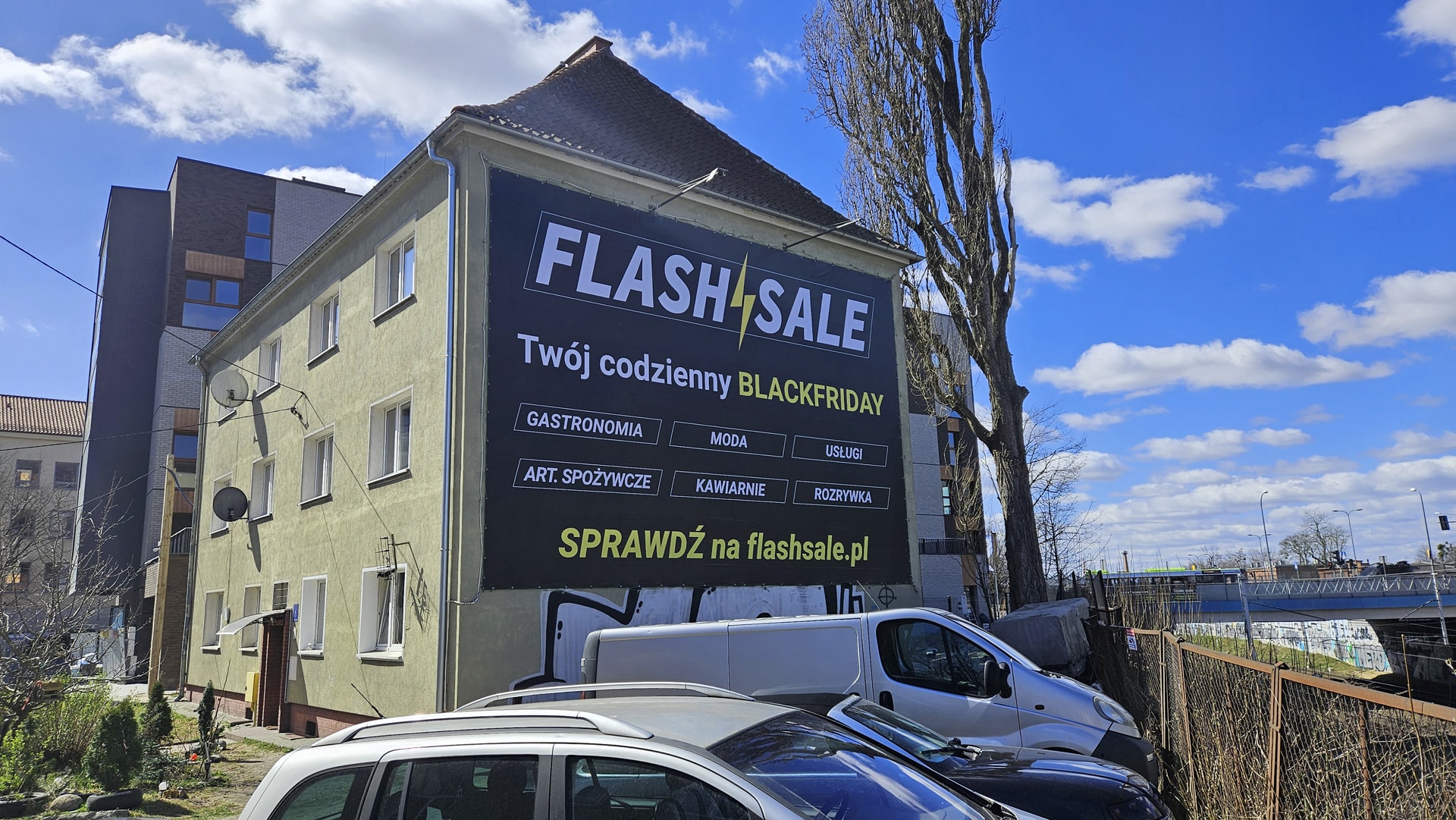 Duży billboard na ścianie budynku promujący platformę FlashSale w Olsztynie, zachęcający lokalne firmy do wsp&oacute;łpracy.