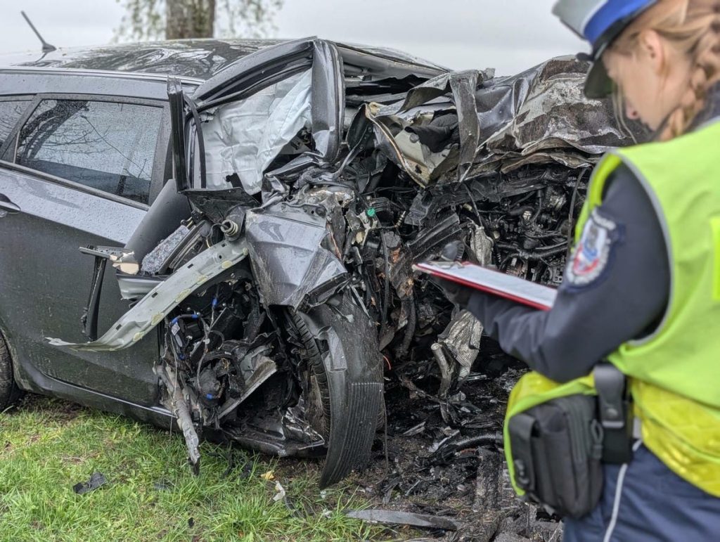 Zniszczony samoch&oacute;d Hyundai po wypadku, na miejscu zdarzenia obecny policjant.