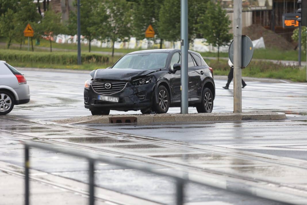 Uszkodzony czarny samochód na skrzyżowaniu w Olsztynie, zderzenie na czerwonym świetle.