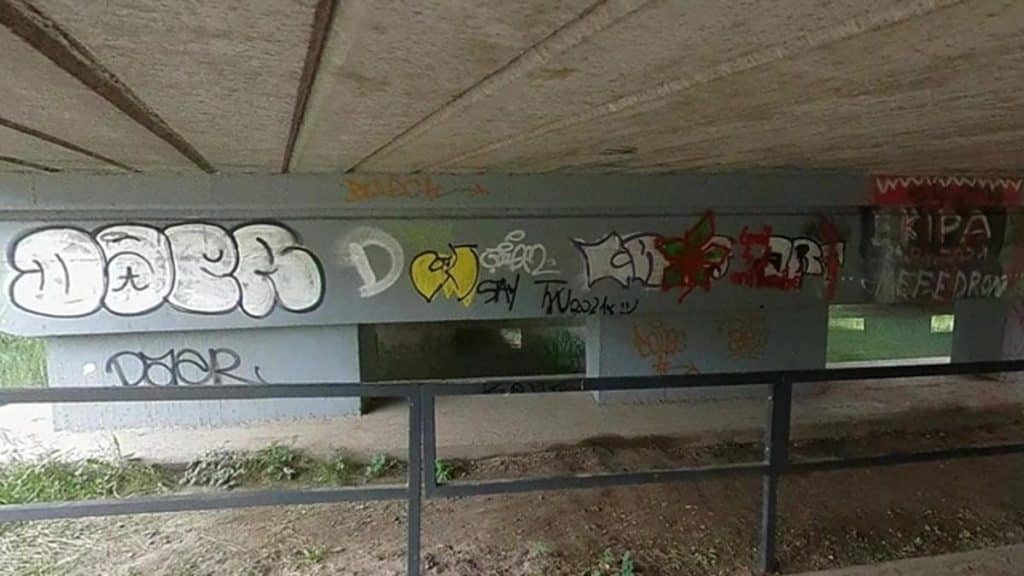 Pod mostem na ścianie znajduje się graffiti i tagi wykonane farbami sprayowymi.