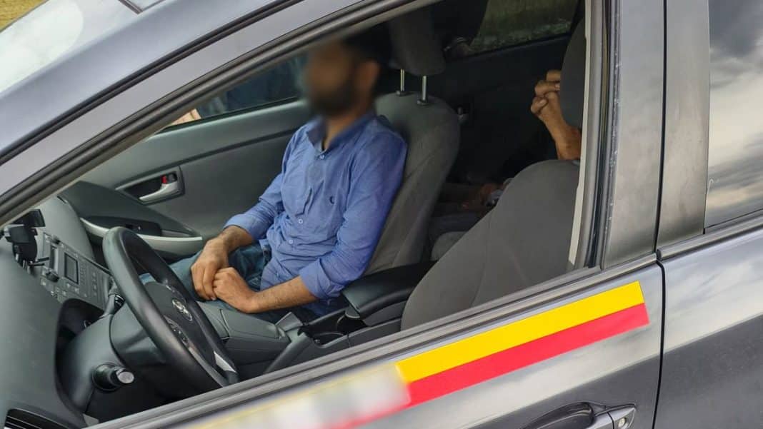 Mężczyzna siedzi za kierownicą czarnej toyoty na drodze krajowej nr 16, w tle widoczny drugi pasażer.