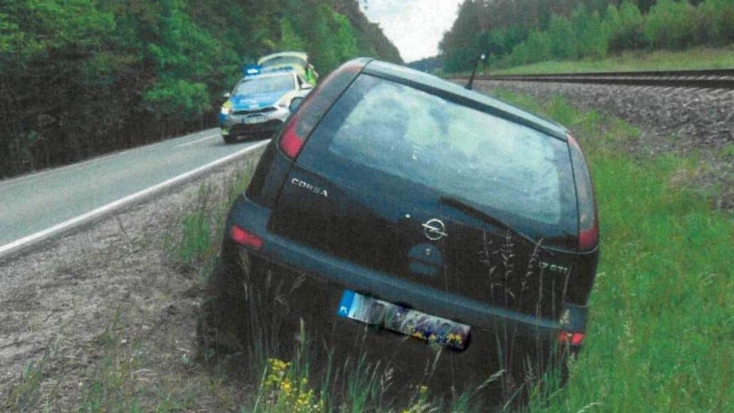 Samochód Opel w rowie przy drodze krajowej, w tle policjantka i radiowóz.