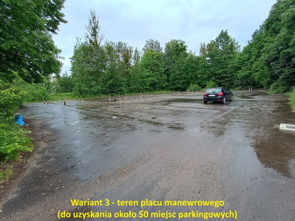 Pusty parking na Zatorzu z kilkoma samochodami i otoczeniem zieleni, na tle pochmurnego nieba.