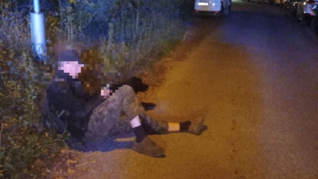 Mężczyzna leżący na poboczu drogi obok psa, wieczorem, w Olsztynie.