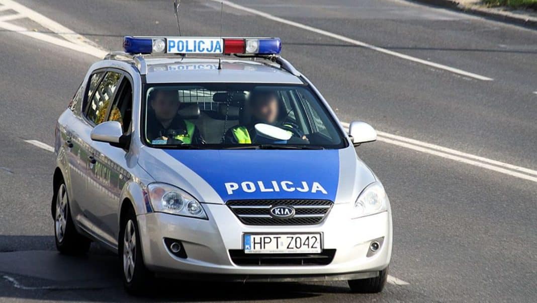 Policja na drodze krajowej nr 16, samochód policyjny na tle jezdni.