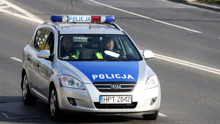 Policja na drodze krajowej nr 16, samochód policyjny na tle jezdni.