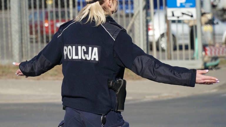 Policjantka w policyjnym uniformie kieruje ruchem na parkingu.