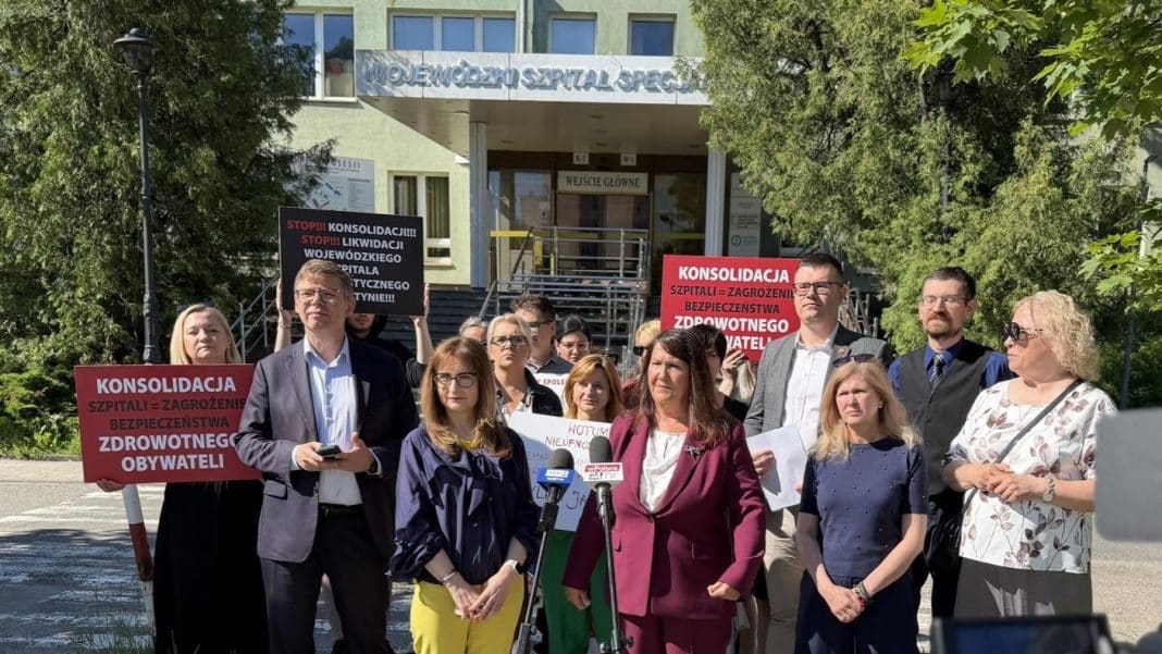 Grupa protestujących z tablicami przed budynkiem szpitala w Olsztynie.
