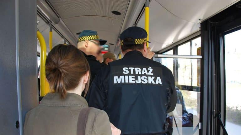 Strażnik miejski w kamizelce kuloodpornej podczas kontroli w autobusie.