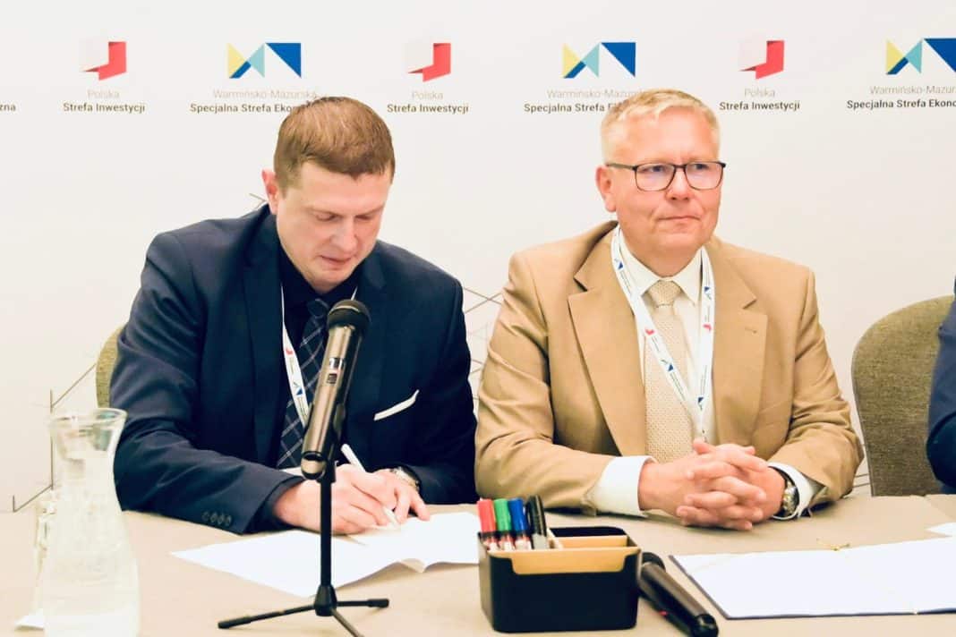 Dwóch mężczyzn podczas konferencji, za nimi logo Strefy Ekonomicznej na ścianie.