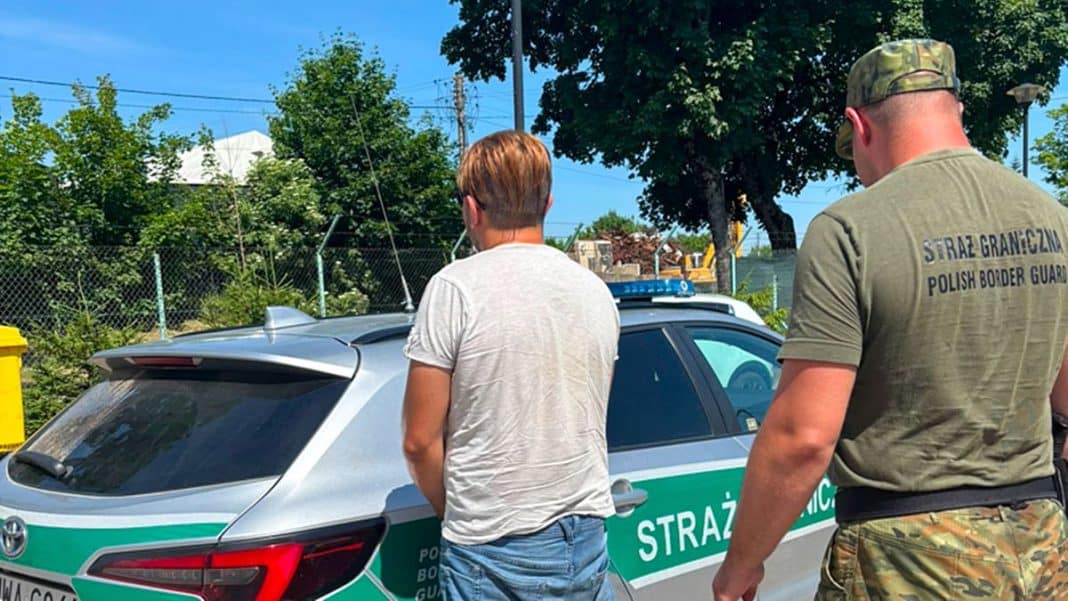 Strażnik graniczny i osoba w białej koszulce przy samochodzie policyjnym na drodze.