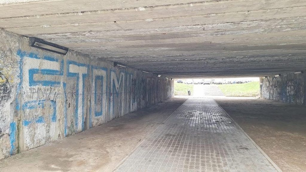 Podziemny przejazd pod ulicą z graffiti na ścianach, w tle widoczny wyjazd na zewnątrz.