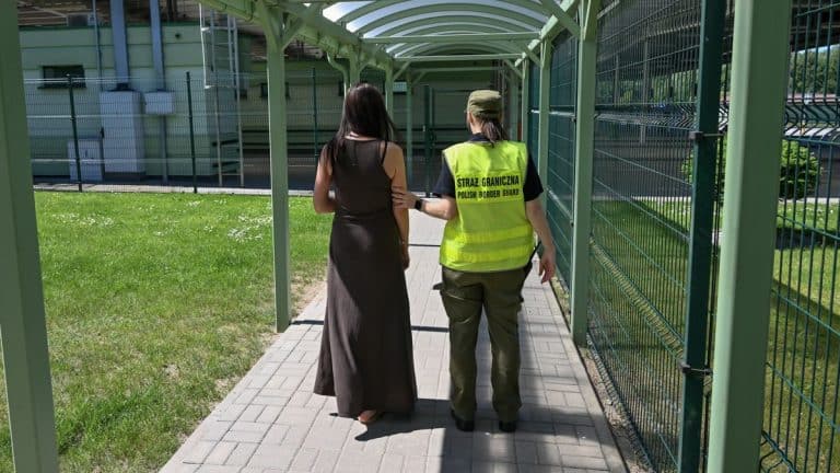 Funkcjonariuszka Straży Granicznej prowadzi kobietę przez przejście graniczne.