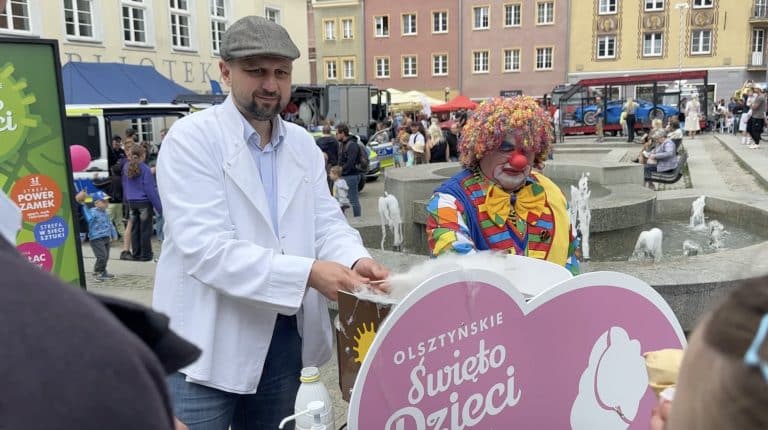 Prezydent Olsztyna rozdaje dzieciom watę cukrową na Starym Mieście podczas Dnia Dziecka.