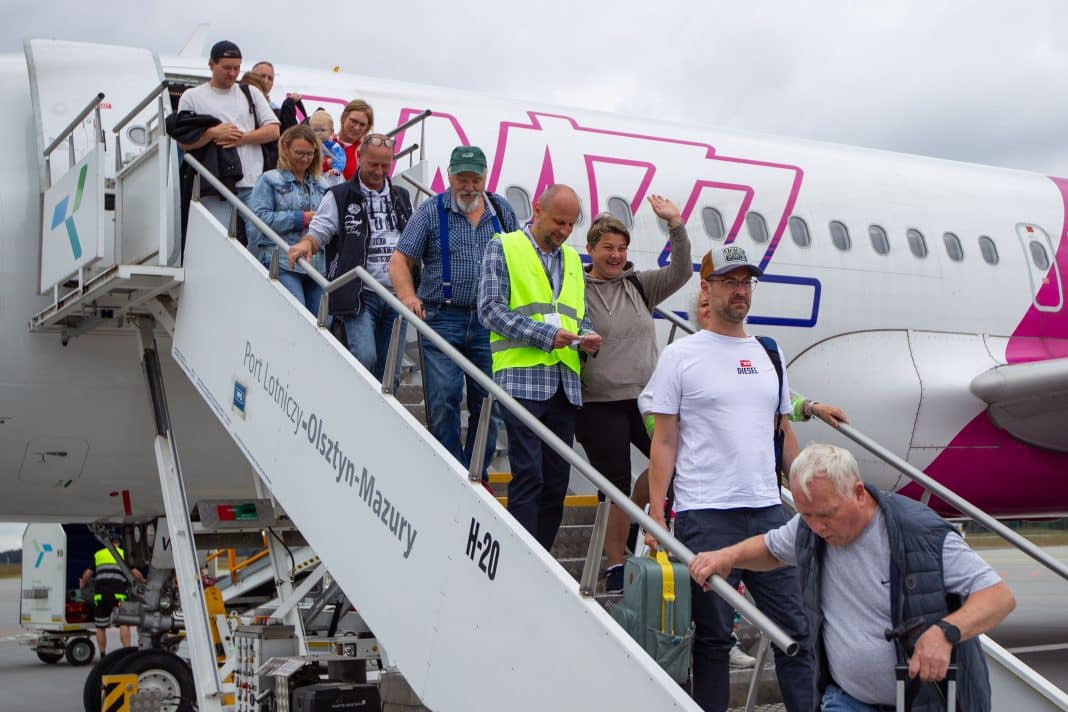 Grupa pasażerów schodzi z samolotu na lotnisku w Szymanach, w tle widać samolot Wizz Air.