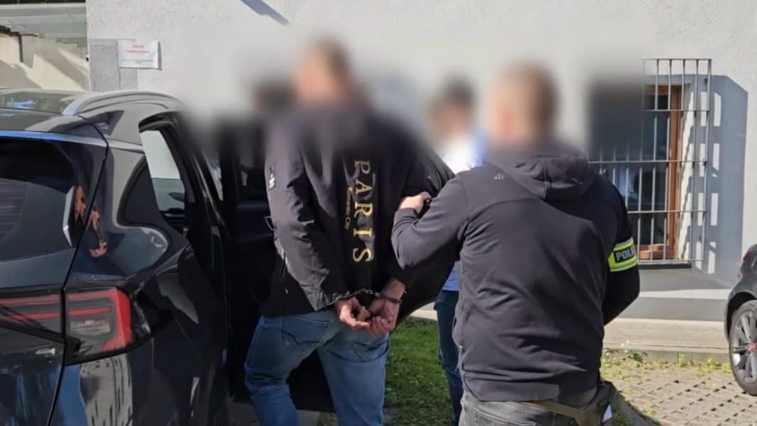 Zatrzymanie mężczyzny przez policję, w tle bloki mieszkalne i samochody.