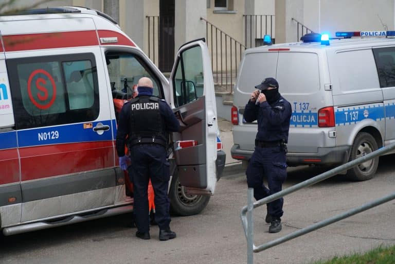 Policjanci na miejscu zdarzenia, obok ambulansu i radiowozu, w trakcie akcji w urzędzie.