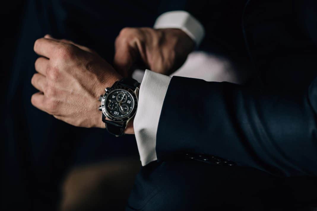 Mężczyzna w eleganckim garniturze sprawdza czas na zegarku na nadgarstku.