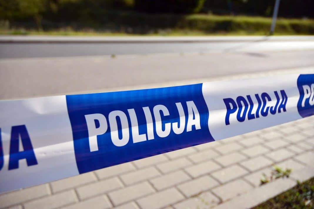 Policja zabezpiecza miejsce zdarzenia przy drodze krajowej, na pierwszym planie taśma policyjna.