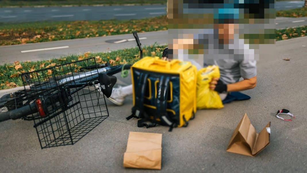 Mężczyzna z rowerem i torbami na ulicy, na chodniku, z rozrzuconymi papierowymi torbami i innymi przedmiotami.