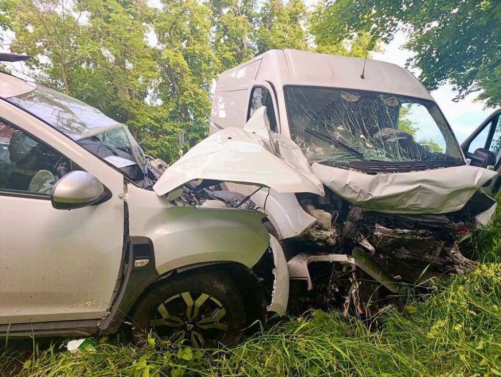 Rozbite pojazdy na drodze po czołowym zderzeniu, z widocznymi uszkodzeniami karoserii.