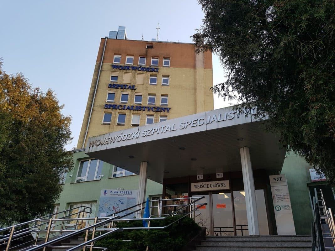 Widok na budynek Wojewódzkiego Szpitala Specjalistycznego w Olsztynie, z napisem na fasadzie.