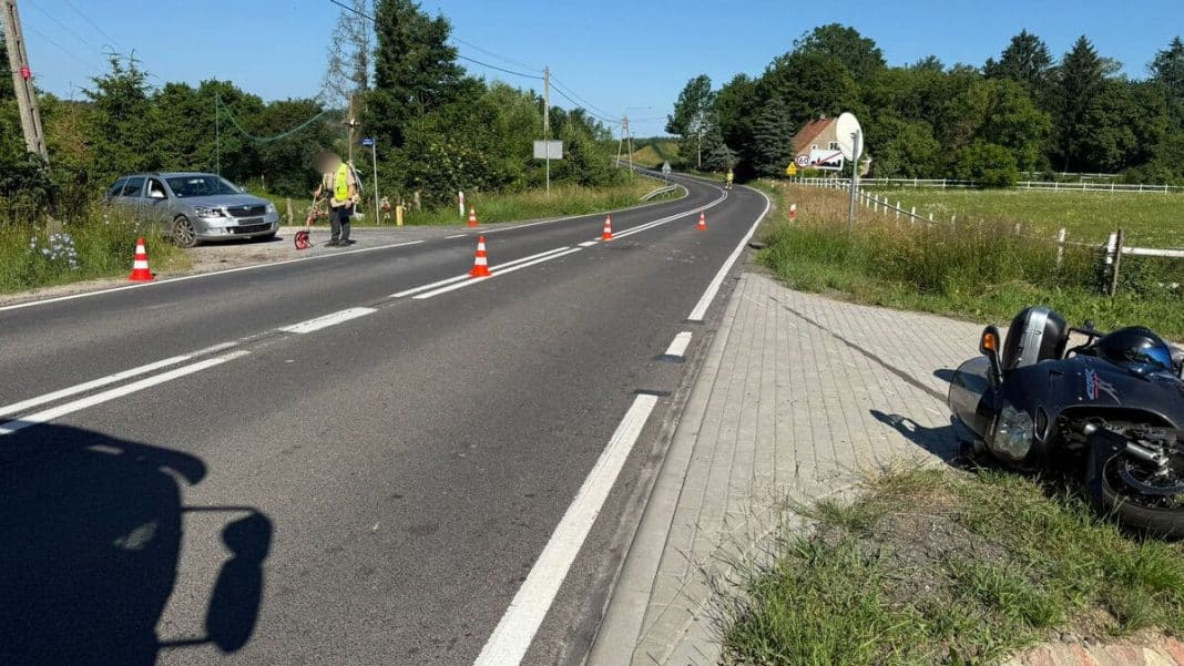 Zderzenie motocyklisty z samochodem Skoda na drodze krajowej, na miejscu policja i zabezpieczenie miejsca zdarzenia.