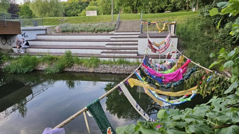 Nietypowy most nad Łyną w Olsztynie, wykonany z materiałów tekstylnych i ozdobnych, połączony z zielonym parkiem.