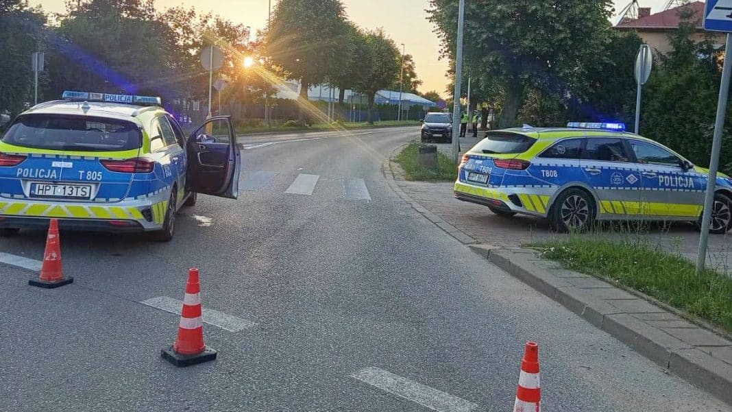 Policja na miejscu wypadku z dwoma radiowozami i oznakowanymi pojazdami na ulicy w Olecku.