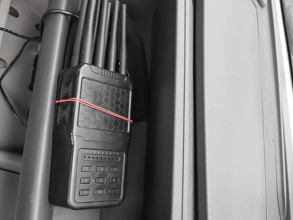 Stary telefon komórkowy na tle metalowej powierzchni, obok kilka rur lub prętów.