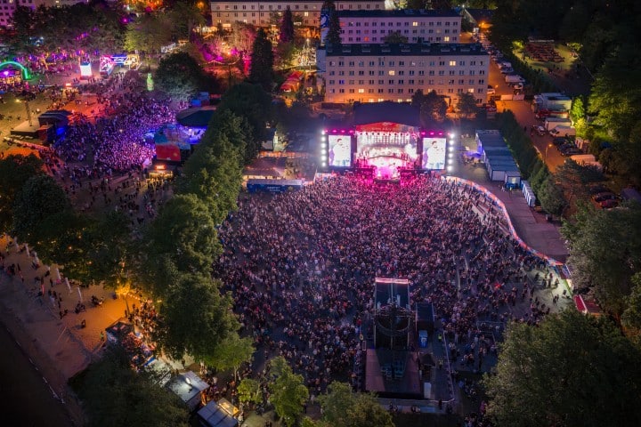 Widok na dużą scenę koncertową na festiwalu Kortowiada 2026 w Olsztynie, otoczoną tłumem uczestników i oświetloną wieczorem.