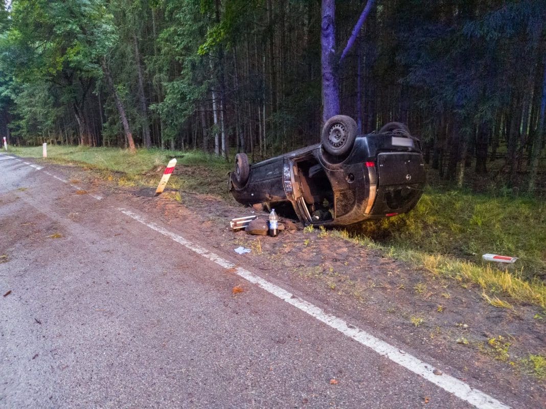 Rozbity samochód na poboczu drogi w lesie, wypadek samochodowy, policja i służby ratunkowe na miejscu.