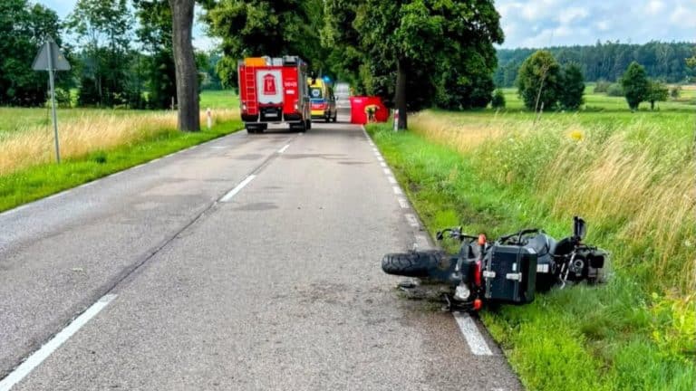 Rozbity motocykl leży na poboczu drogi, w tle pojazdy służb ratunkowych, na drodze krajowej nr 610.
