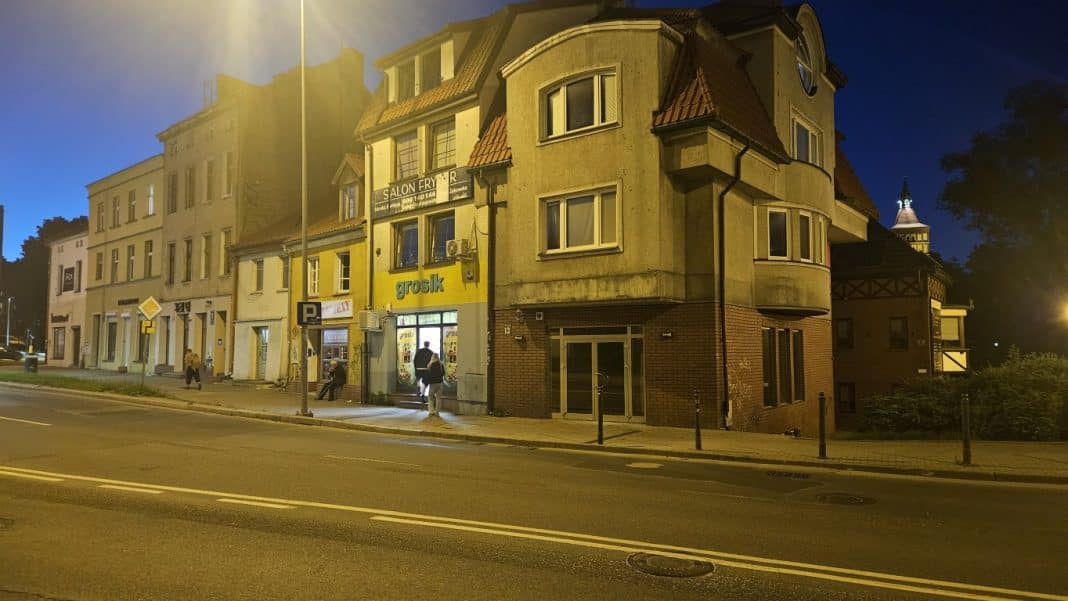 Widok na budynek sklepu Alkohole Winoteka w Olsztynie nocą, z widocznym wejściem i oznaczeniem