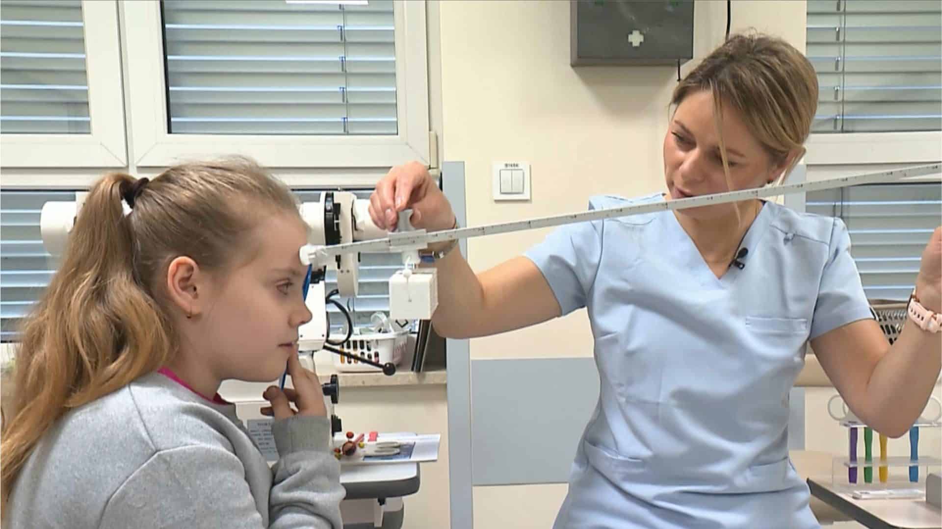 Lekarka badająca wzrok dziewczynki w gabinecie okulistycznym.
