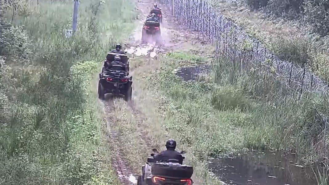 Grupa mężczyzn jadących quadami wzdłuż granicy z Rosją, w terenie z zielenią i drzewami.