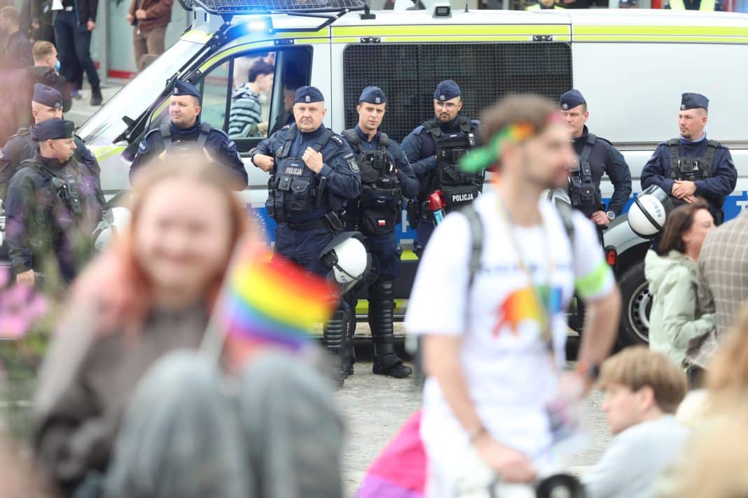 Policjanci na tle pojazdu podczas interwencji podczas Marszu Równości w Olsztynie.