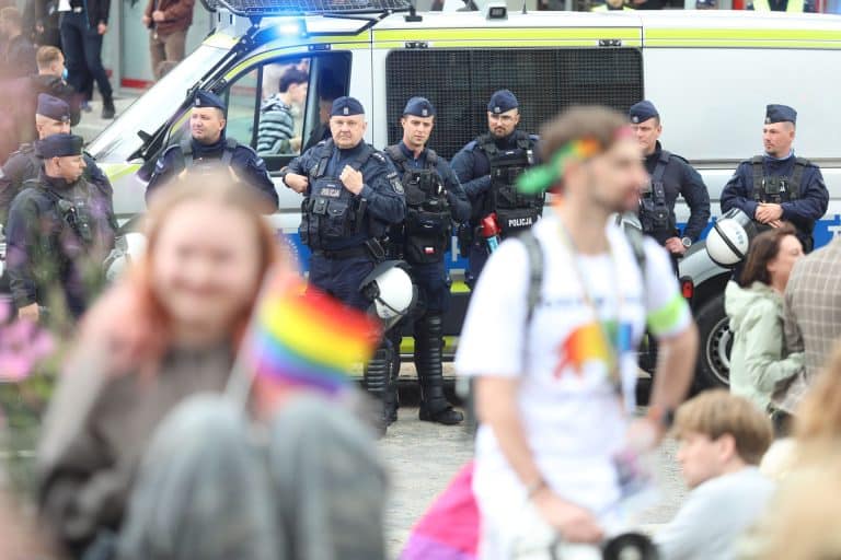Policjanci na tle pojazdu podczas interwencji podczas Marszu Równości w Olsztynie.