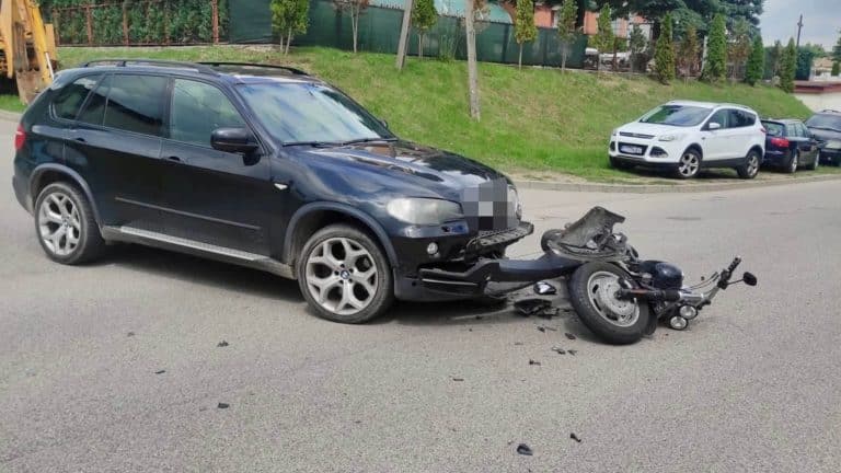 Rozbity motocykl i uszkodzone BMW po zderzeniu na ulicy w Mrągowie.