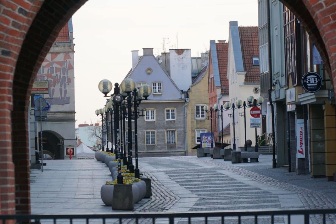 Ulica w centrum Olsztyna z oświetleniem i pustymi ławkami, widok na historyczne budynki.