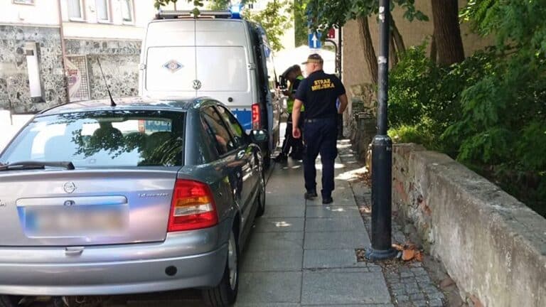 Straż miejska i policja na Starym Mieście w Olsztynie, odholowują samochód zaparkowany niezgodnie z przepisami.