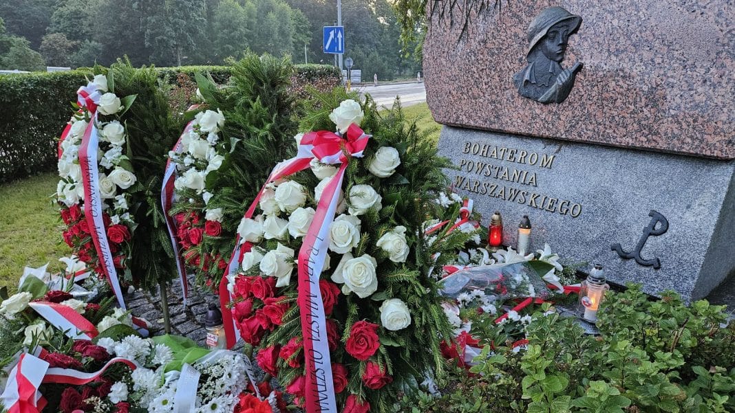 Kwiaty i znicze przed pomnikiem powstańców warszawskich w Olsztynie.