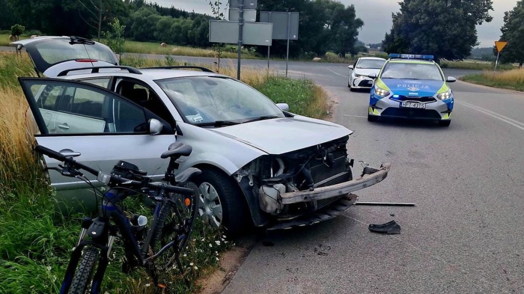 Rozbity samochód po czołowym zderzeniu na drodze, policja na miejscu zdarzenia.