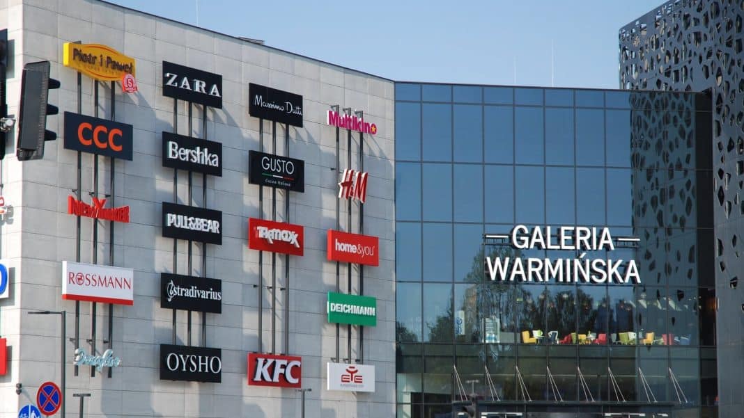 Widok na zewnętrze Galerii Warmińskiej z logo sklepów i nazwą galerii.