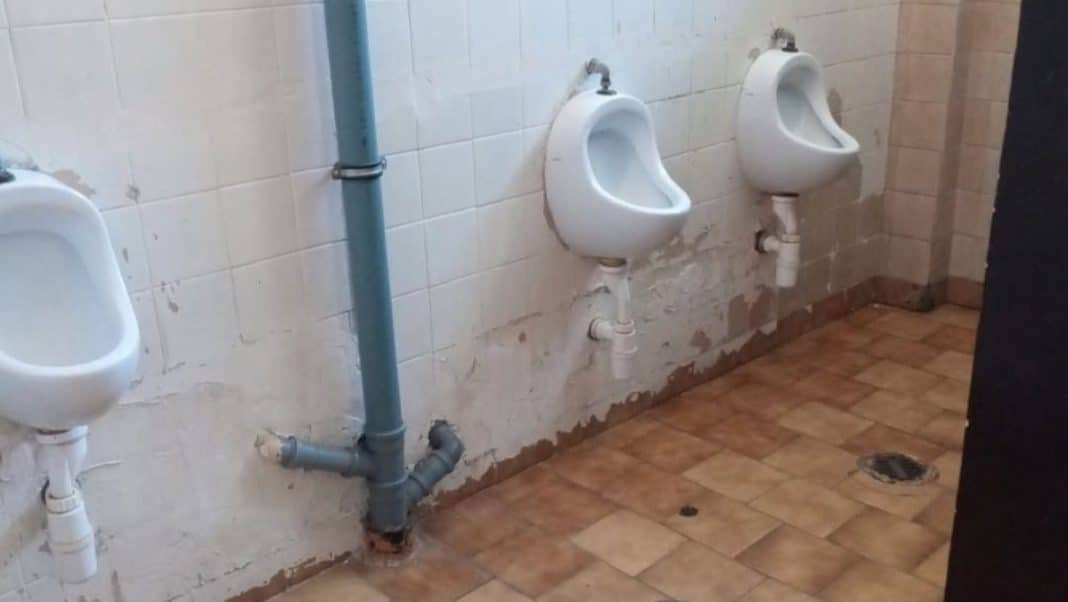 Zdjęcie zniszczonych okien, tynków i placu zabaw na terenie szkoły, widoczne uszkodzenia budynku.