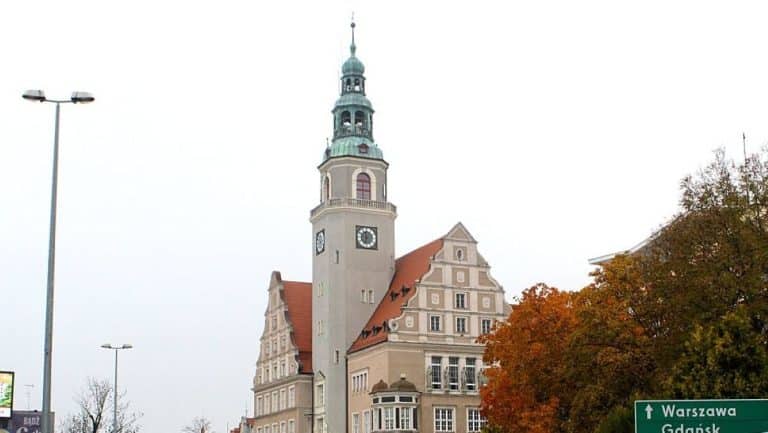 Widok na ratusz w Olsztynie z wieżą zegarową i drzewami o jesiennych kolorach.