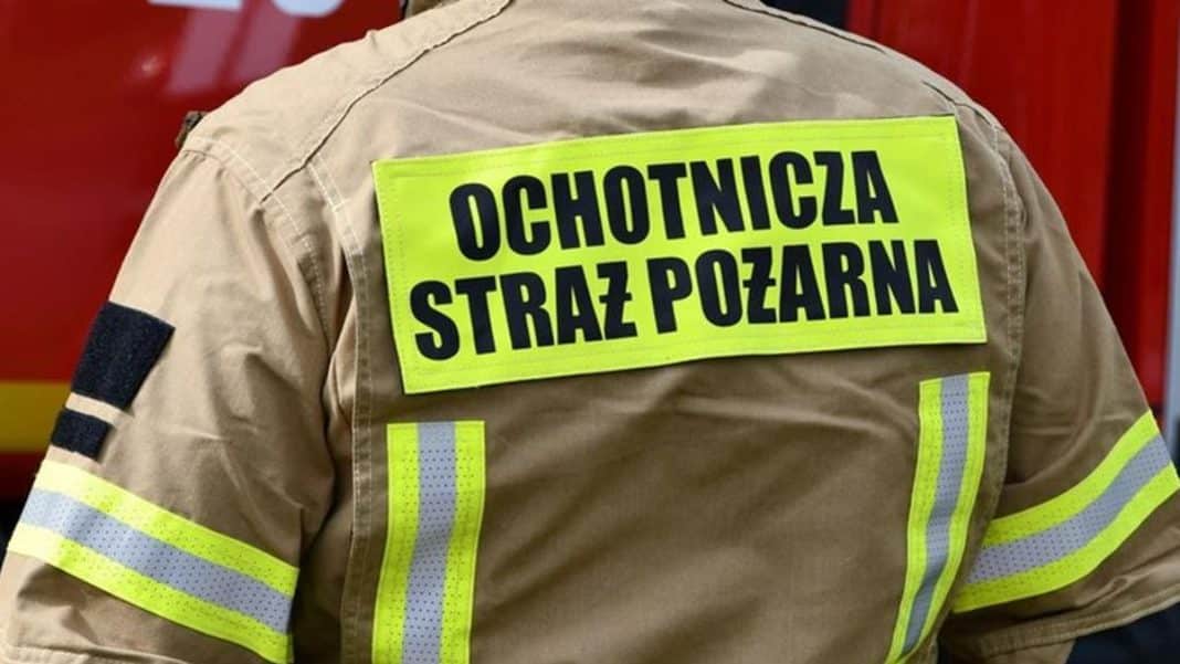 Ubranie strażaka z napisem 'Ochotnicza Straż Pożarna' na plecach, widziane od tyłu.